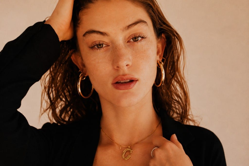 Model in chunky gold hoops and a delicate initial pendant — Undaunted Treasure Trove signature looks
